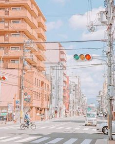 a man riding a bike down a street next to tall buildings and traffic lights on poles