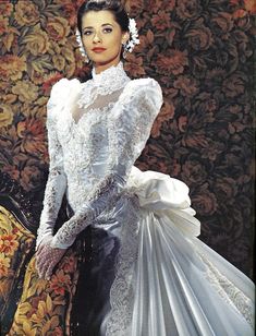 a woman in a white wedding dress standing next to a floral wall