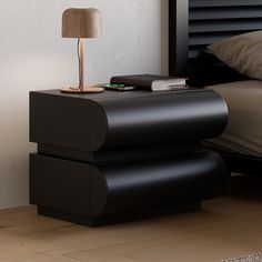 a nightstand with a lamp on top of it next to a bed