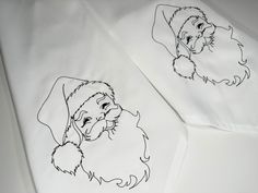 two white sheets with black ink drawings of santa claus and a dog on them,