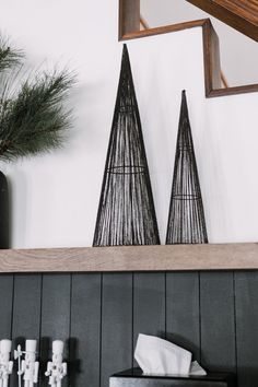 two black and white christmas trees on top of a mantle