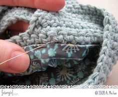 someone is stitching together the fabric to make a crochet purse or bag