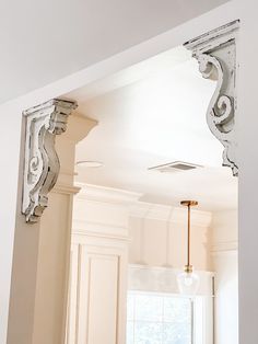 an ornate white mirror hanging on the wall above a sink in a room with beige walls