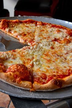 a pizza sitting on top of a metal pan with a spatula in it's hand