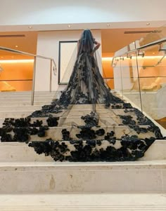 a woman is walking up some stairs wearing a dress that has flowers on the bottom