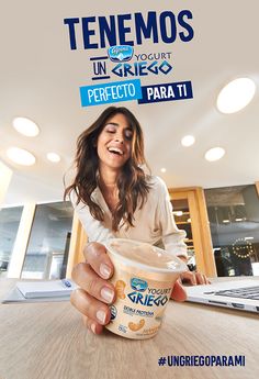 a woman sitting at a table with a cup of ice cream in front of her