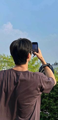 a man taking a photo with his cell phone in front of the eiffel tower