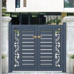 an iron gate with decorative designs on the top and bottom bars, in front of a building