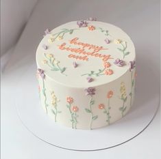 a birthday cake decorated with flowers and the words happy birthday on it's side