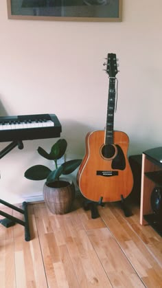 an acoustic guitar sitting on the floor next to a piano