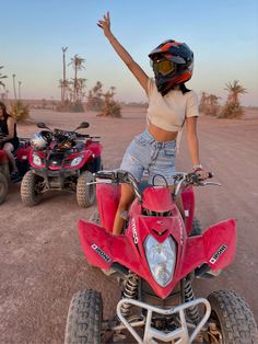 a woman riding on the back of a red four - wheeler with two people in the background