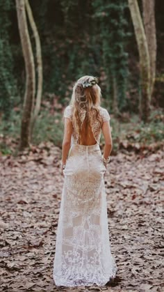 a woman standing in the woods with her back to the camera and wearing a white dress