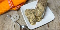 a bottle and spoon sitting on a plate next to a towel, salt and pepper shaker