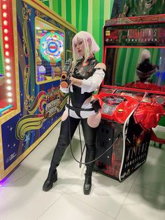 a woman in black and white outfit standing next to an arcade machine