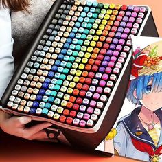 a woman is holding a large keyboard made out of colored pencils and paper with an anime character drawn on it