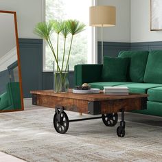 a living room with green couches and a coffee table in front of a mirror