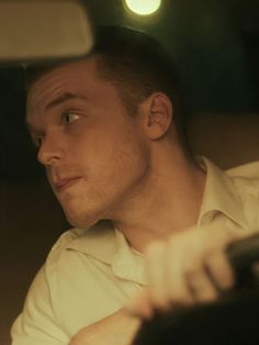 a man sitting in the passenger seat of a car looking at something off to the side