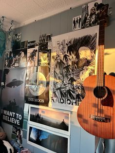 a room with guitars and posters on the wall, including an acoustic guitar hanging from the ceiling