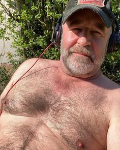 an older man with no shirt wearing headphones on his ears and looking at the camera