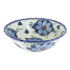 a blue and white bowl with flowers on the rim, sitting in front of a white background