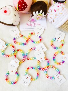 colorful bracelets are laid out on a white surface next to stuffed animals and cards