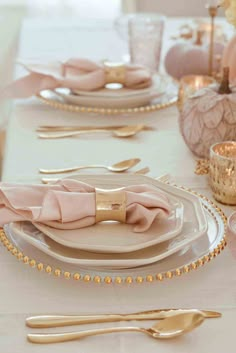 the table is set with pink and gold place settings