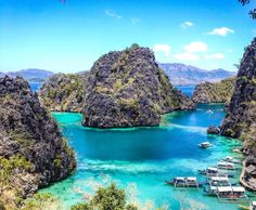 boats are docked in the clear blue water at an island with many rocks and cliffs