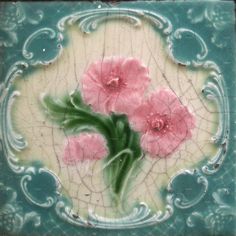 some pink flowers are painted on a blue and white tile wall ornament,