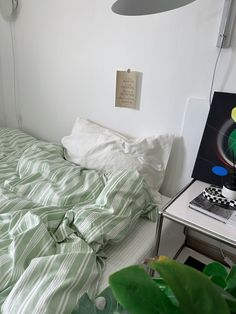 a bed sitting next to a green plant in a bedroom