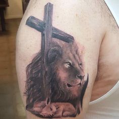 a man with a lion and cross tattoo on his shoulder is holding a baby jesus