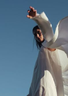 a woman in white is flying through the air with her arms out to catch something