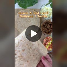 a person is holding a tortilla in front of some other food on a table