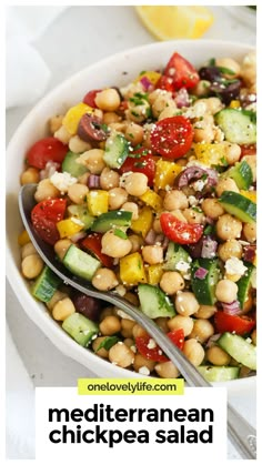 a white bowl filled with chickpea salad next to a fork and lemon wedge