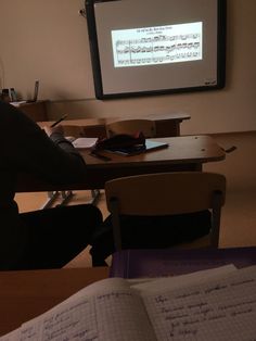 a person sitting at a desk in front of a projector screen with music notes on it