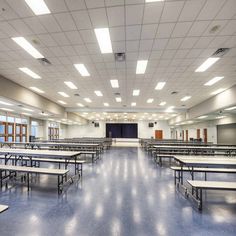 an empty classroom with tables and benches in the middle, lights are on above them