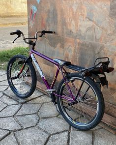 a purple bike leaning against a stone wall