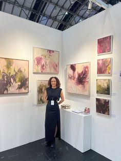 a woman standing in front of some paintings