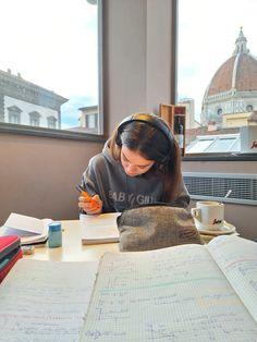 a woman sitting at a table in front of an open book with headphones on