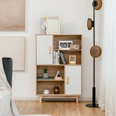 a living room with white walls and wooden flooring on the hardwood floors, an open shelving unit is next to a black chair