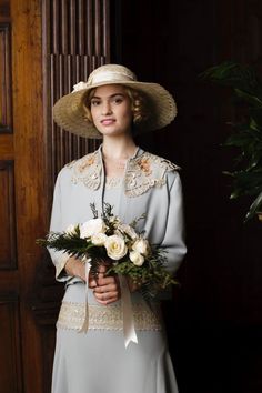 a woman in a dress and hat holding flowers