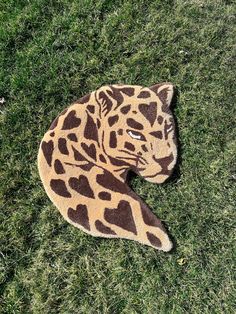 a stuffed giraffe laying on top of a green grass covered field with it's eyes open