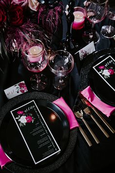 the table is set with black and pink place settings