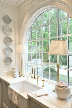 a kitchen with an arched window, sink and lamp on the counter next to it