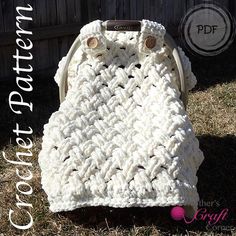 a white crocheted bag sitting on top of grass next to a wooden fence