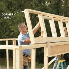 two men are working on the framing of a house that's being built in front of some trees