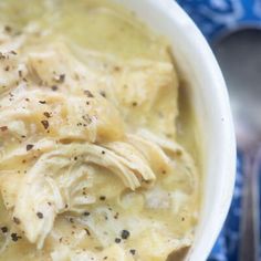 a white bowl filled with chicken and dumplings on top of a blue table cloth