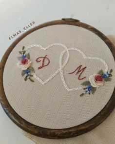 two hearts with flowers and the word dm on them are in a wooden hoop