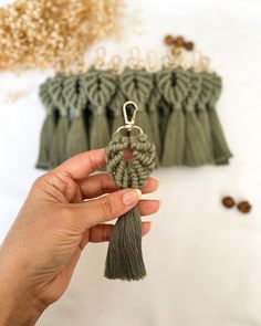 a hand holding a keychain with two tassels attached to it, next to other tassels