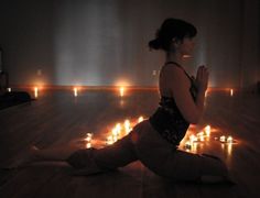 a woman sitting on the floor in front of candles