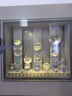 a display case filled with lots of different types of plates and vases on glass shelves